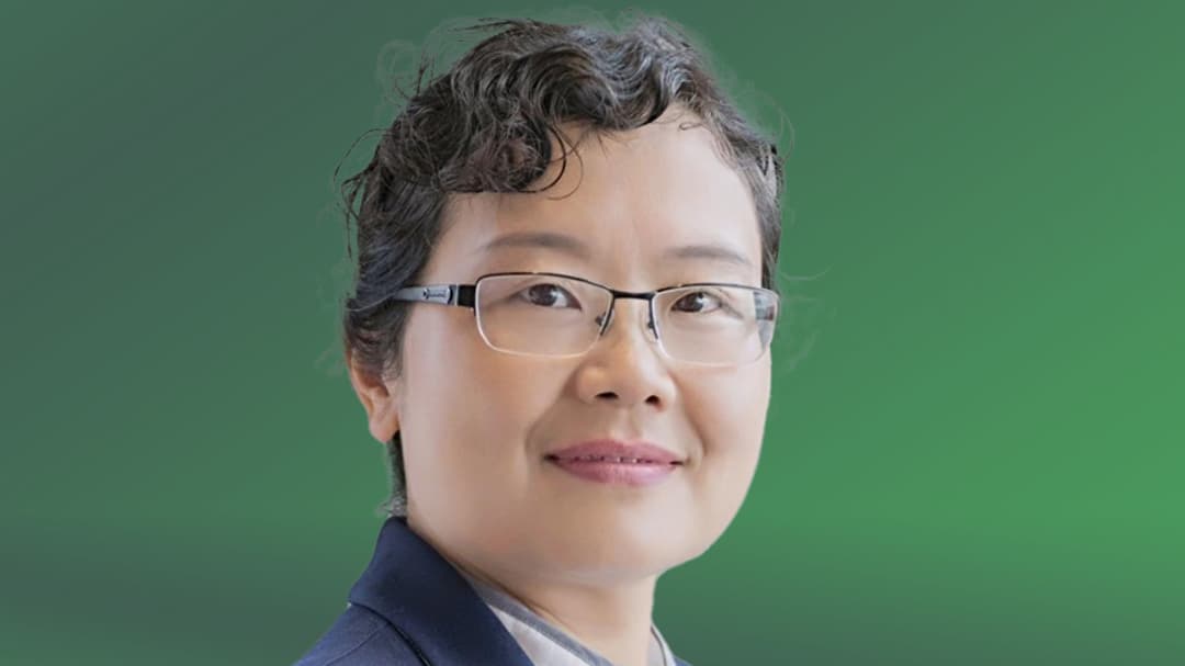 A woman with glasses looks into the camera.