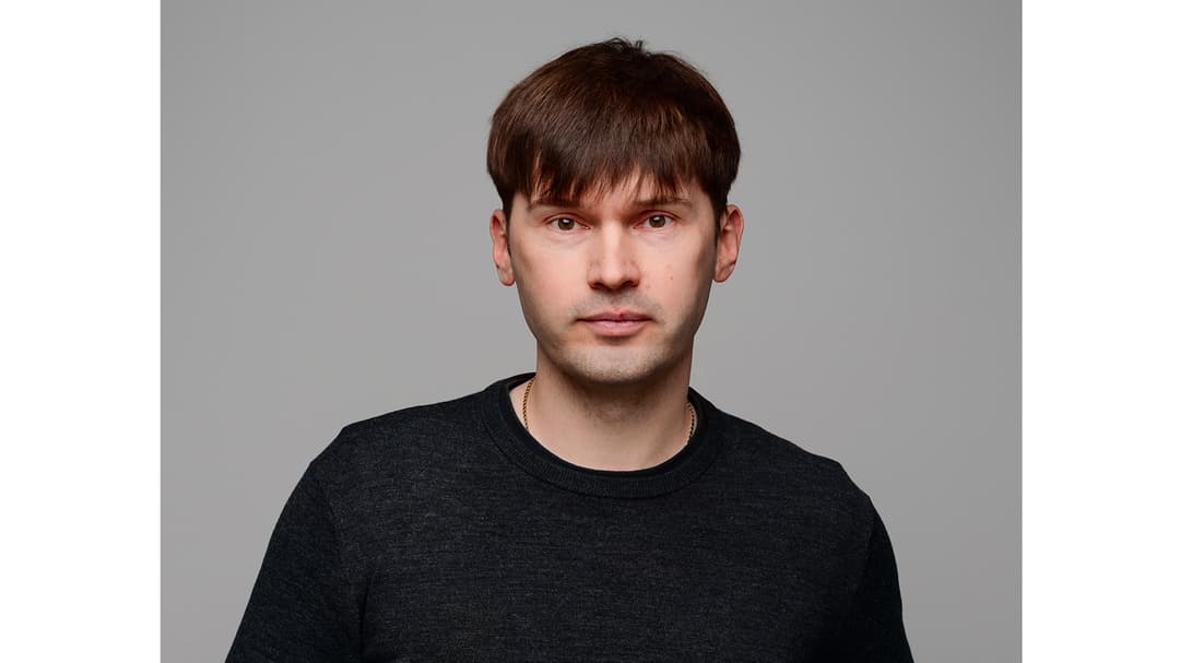 A man with dark, short hair, wearing a black shirt.